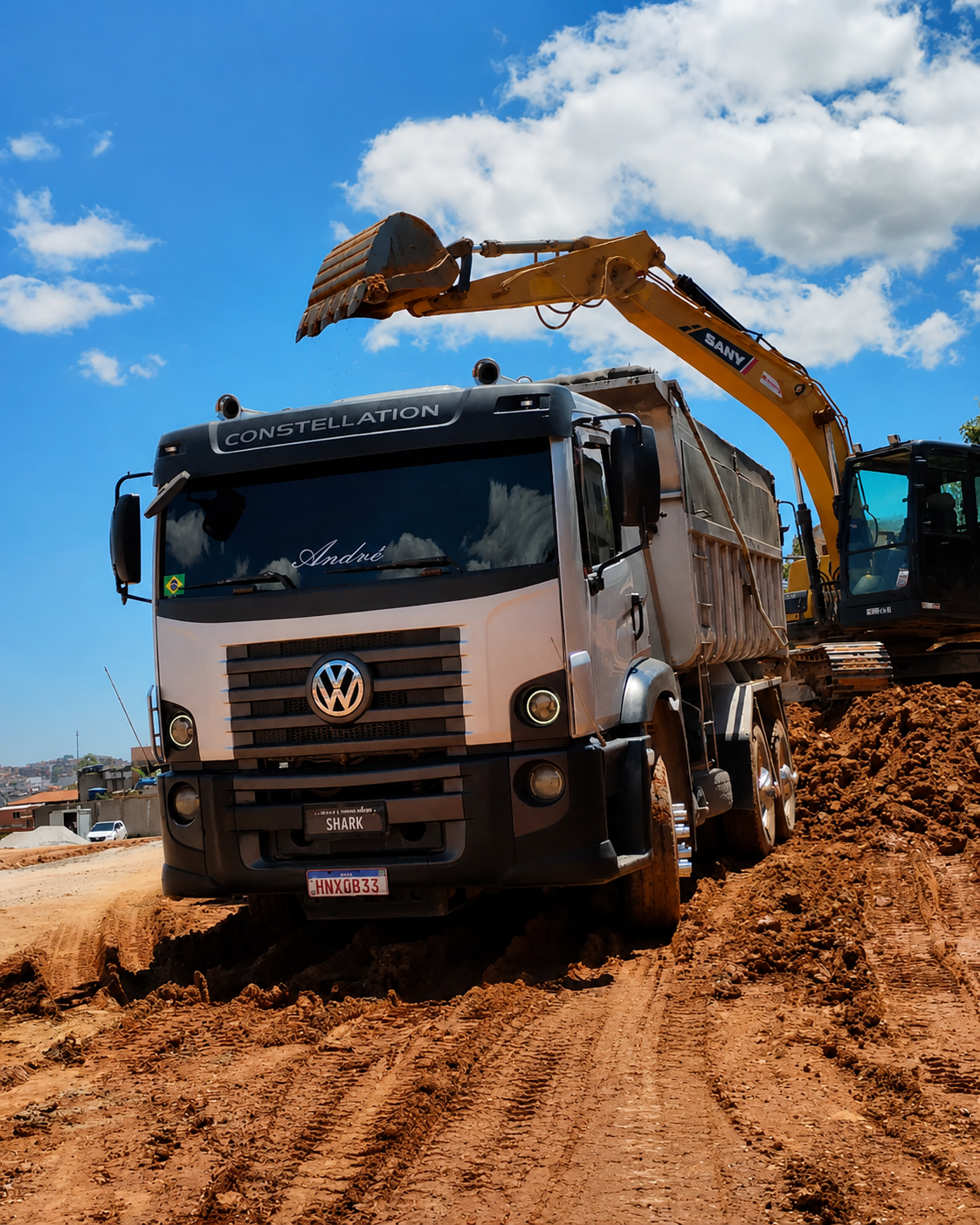 Caminhão basculante e escavadeira em operação de terraplenagem